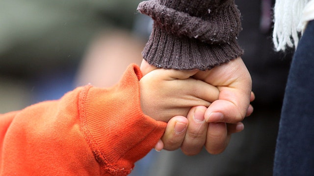 Mother Claudia Garcia from Danbury, Connecticut, holds her son Julian's hand tightly as they view the shrine set up around the towns Christmas tree in Sandy Hook after the mass shootings at Sandy Hook Elementary School, Newtown, Connecticut, USA. 17th December 2012. Photo Tim Clayton (Photo by Tim Clayton/Corbis via Getty Images)
