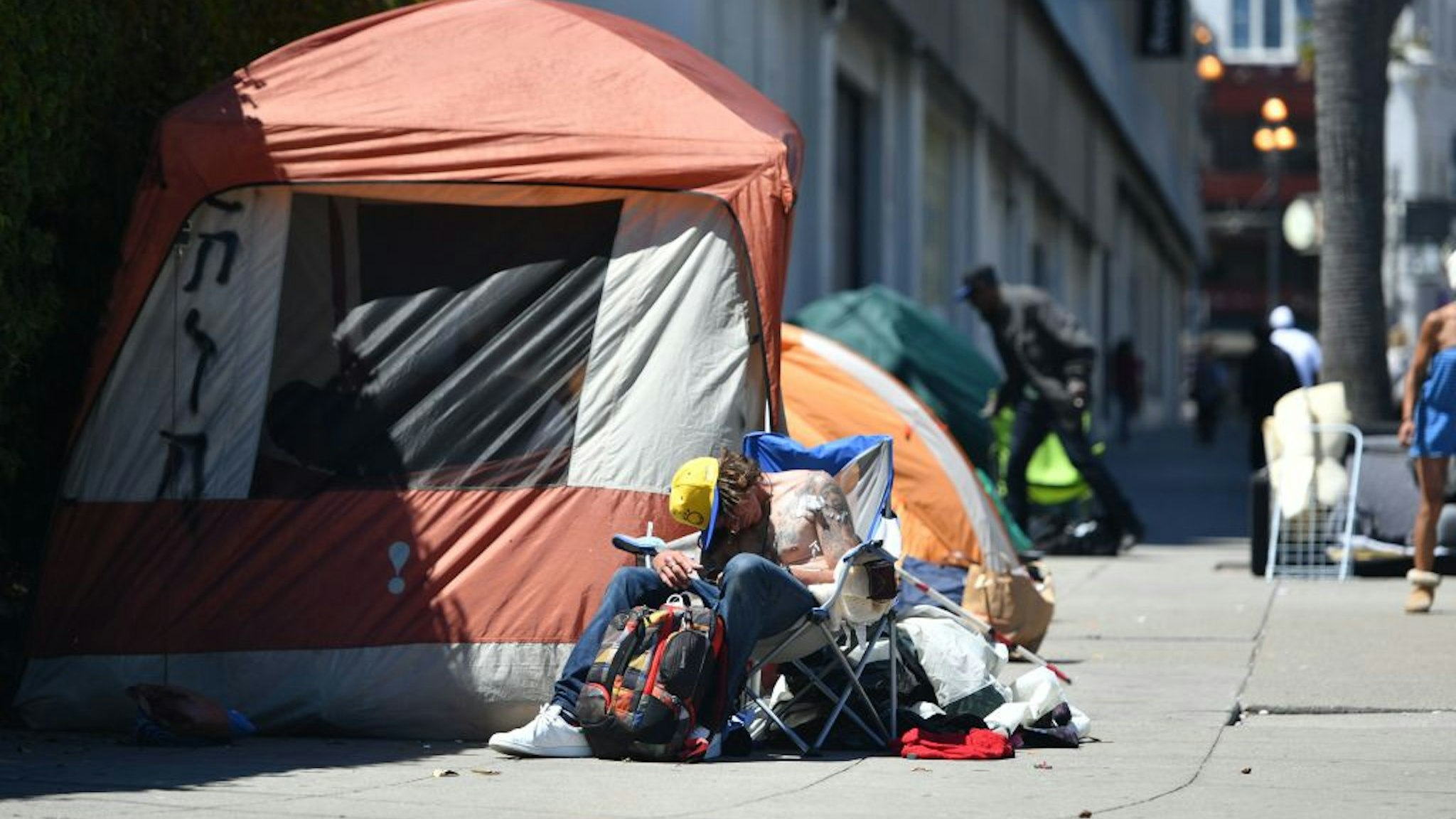 A homeless man sleeps in front of his tent along Van Ness Avenue in downtown San Francisco, California on June, 27, 2016. Homelessness is on the rise in the city irking residents and bringing the problem under a spotlight. (Photo by Josh Edelson / AFP) (Photo credit should read JOSH EDELSON/AFP via Getty Images)
