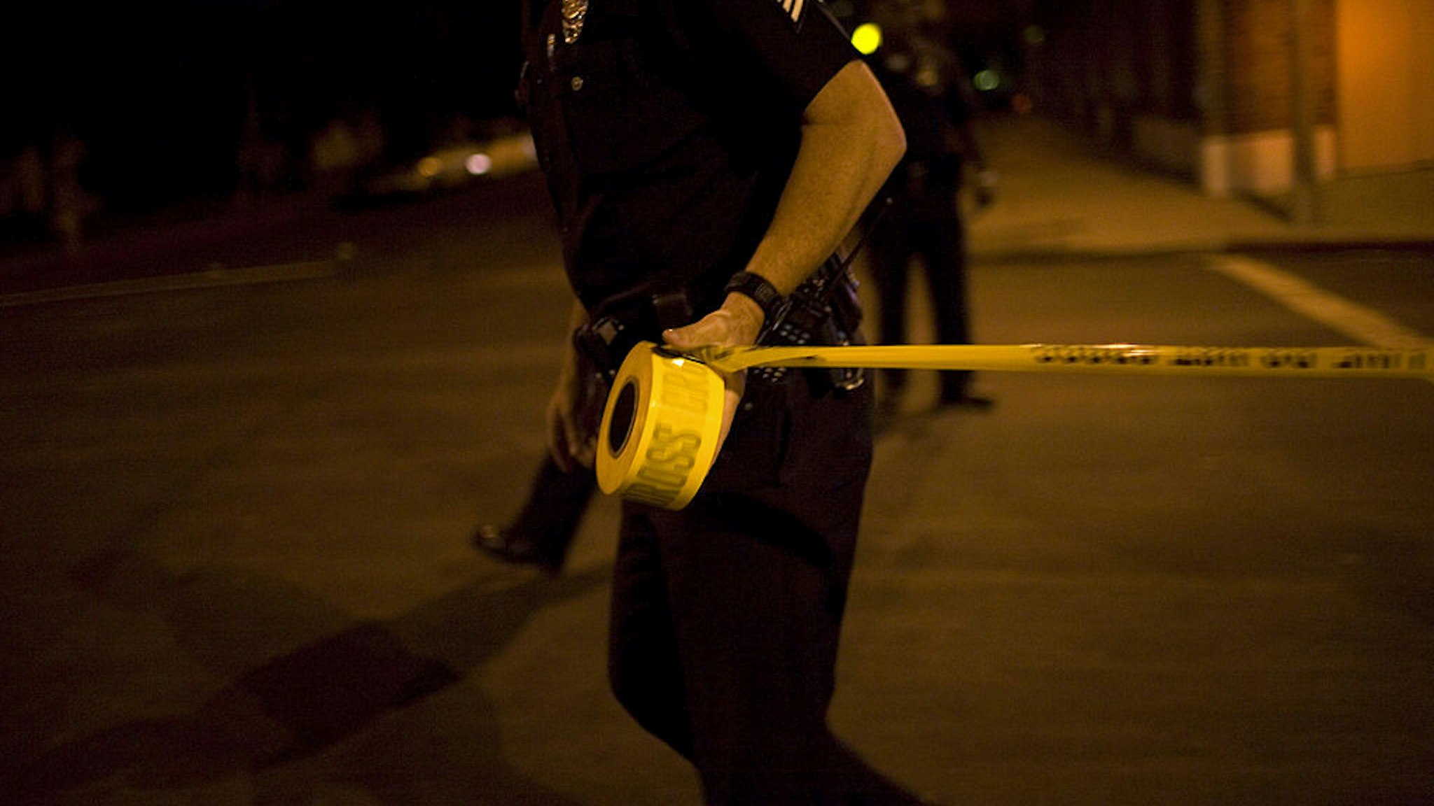 LOS ANGELES - SEPTEMBER 14: Los Angeles Police Department gang unit officers tape off a Crime Scene Investigation area following the shooting of a man September 14, 2007 in the Northeast precinct of Los Angeles, California. The injured man was taken to a nearby hospital after his assailant escaped. Police detectives questioned the victim's girlfriend, who arrived after the shooting, when a pistol was found inside her car. The LAPD gang unit is part of the Rampart police precinct where MS-13 and Hispanic street gangs have plagued local neighborhoods for decades. (Photo by Robert Nickelsberg/Getty Images)