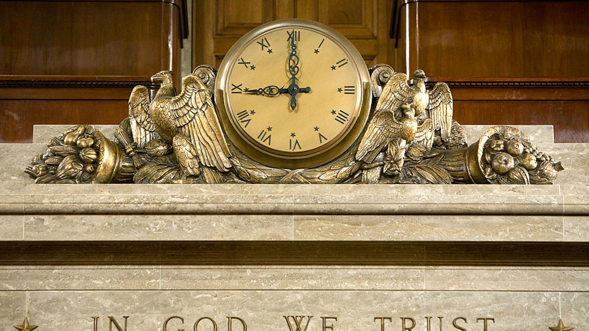 WASHINGTON - DECEMBER 8: A clock and the motto "In God We Trust" over the Speaker's rostrum in the U.S. House of Representatives chamber are seen December 8, 2008 in Washington, DC. Members of the media were allowed access to film and photograph the room for the first time in six years. (Photo by Brendan Hoffman/Getty Images)