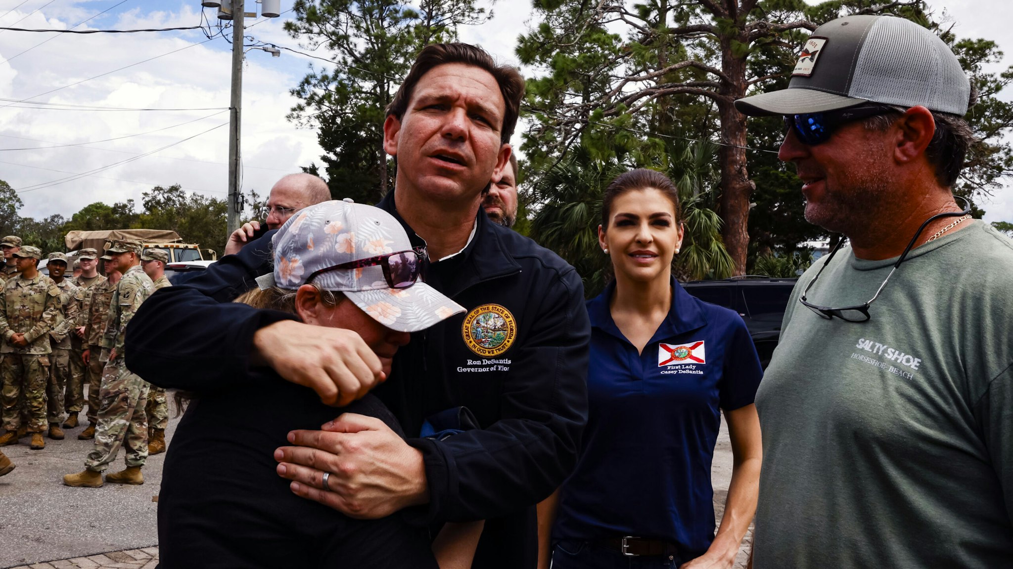 Ron DeSantis, governor of Florida and 2024 Republican presidential candidate, center left, embraces a resident during a visit after Hurricane Idalia in Horseshoe Beach, Florida, US, on Thursday, Aug. 31, 2023. Florida has started to dig out from the aftermath of Idalia, which weakened to a tropical storm even as it brought heavy rain across Georgia and the Carolinas, caused billions of dollars in damage, left hundreds of flights grounded and thousands without power.