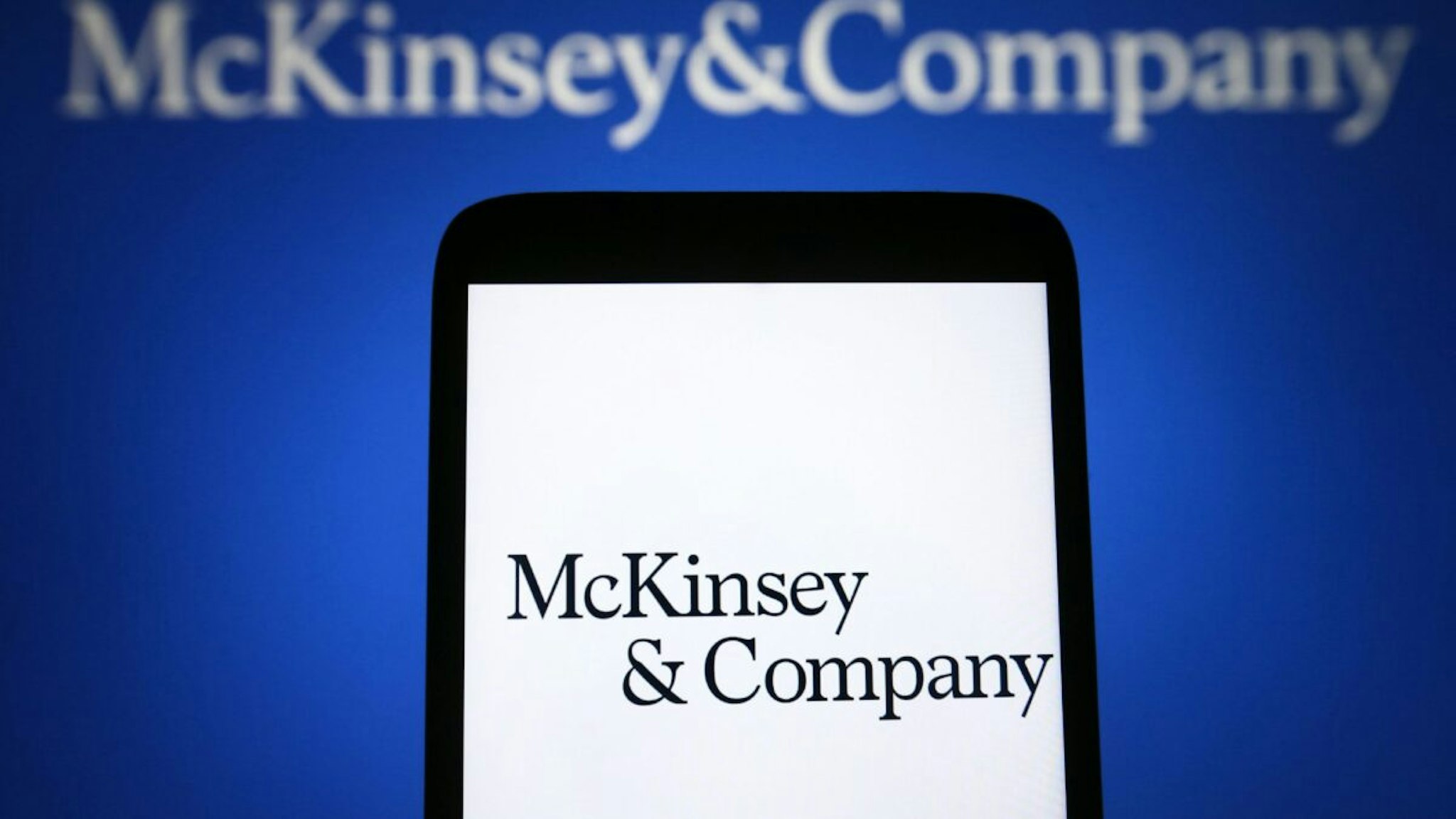In this photo illustration, a McKinsey & Company logo is seen on a smartphone and on a pc screen.