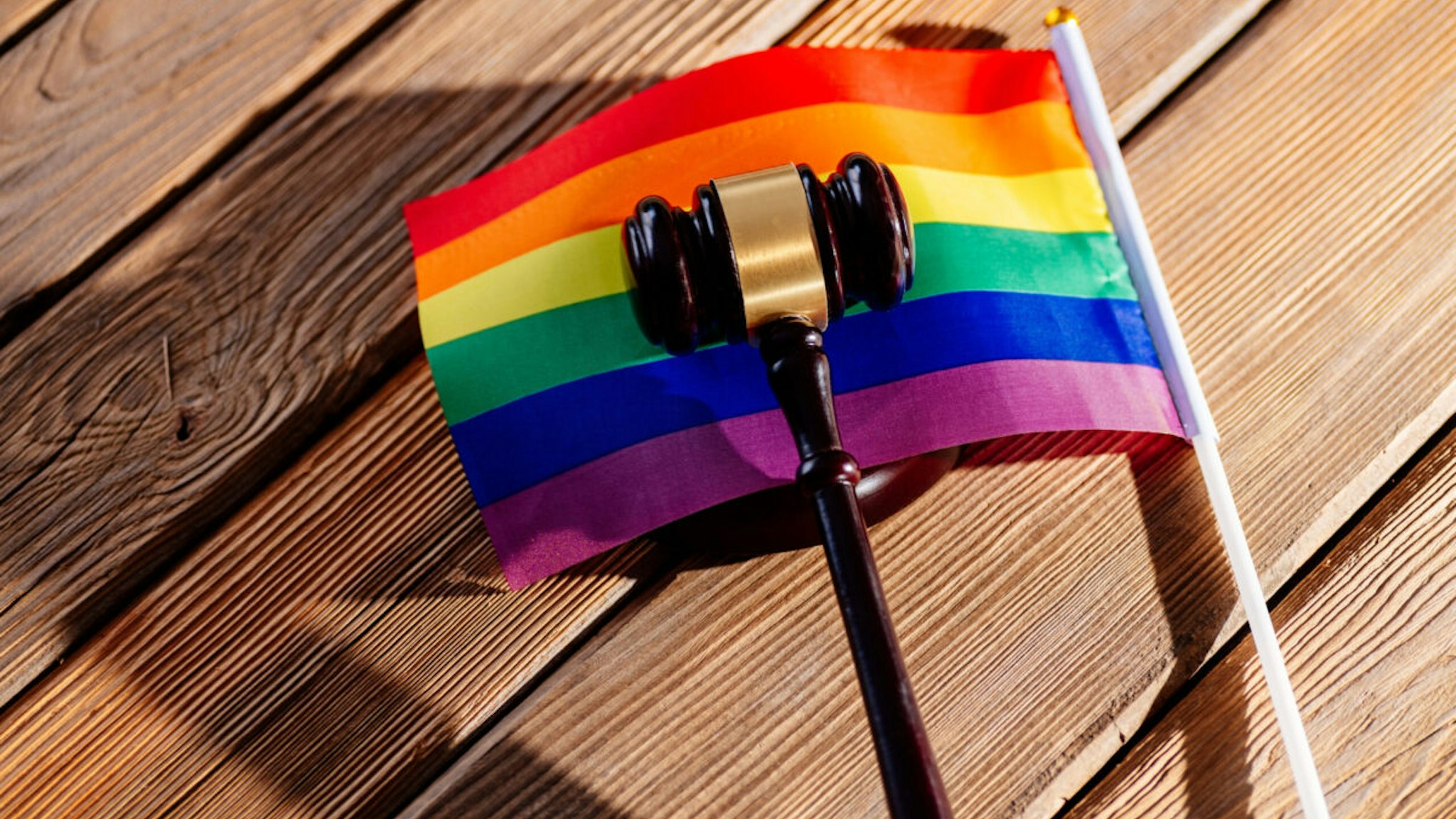 Judge wooden mallet - symbol of law and justice with lgbt rainbow colours flag. Lgbt rights and law