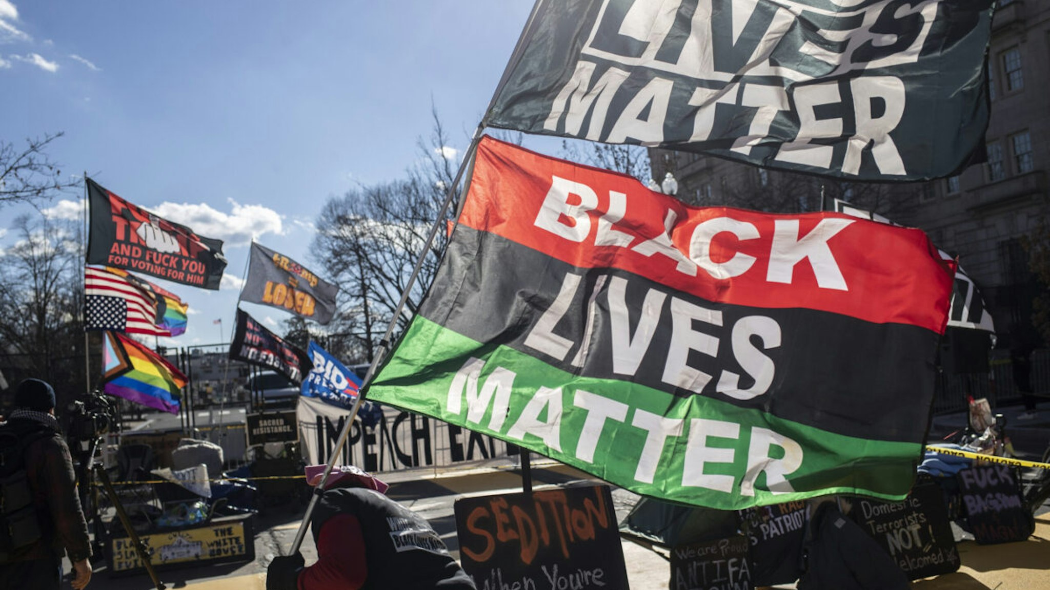 Demonstrators wave flags at Black Lives Matter Plaza in Washington, D.C., U.S., on Tuesday, Jan. 19, 2021. President-elect Joe Biden is set to arrive in Washington on Tuesday, the eve of his inauguration, with the usual backdrop of celebrations and political comity replaced by a military lockdown.