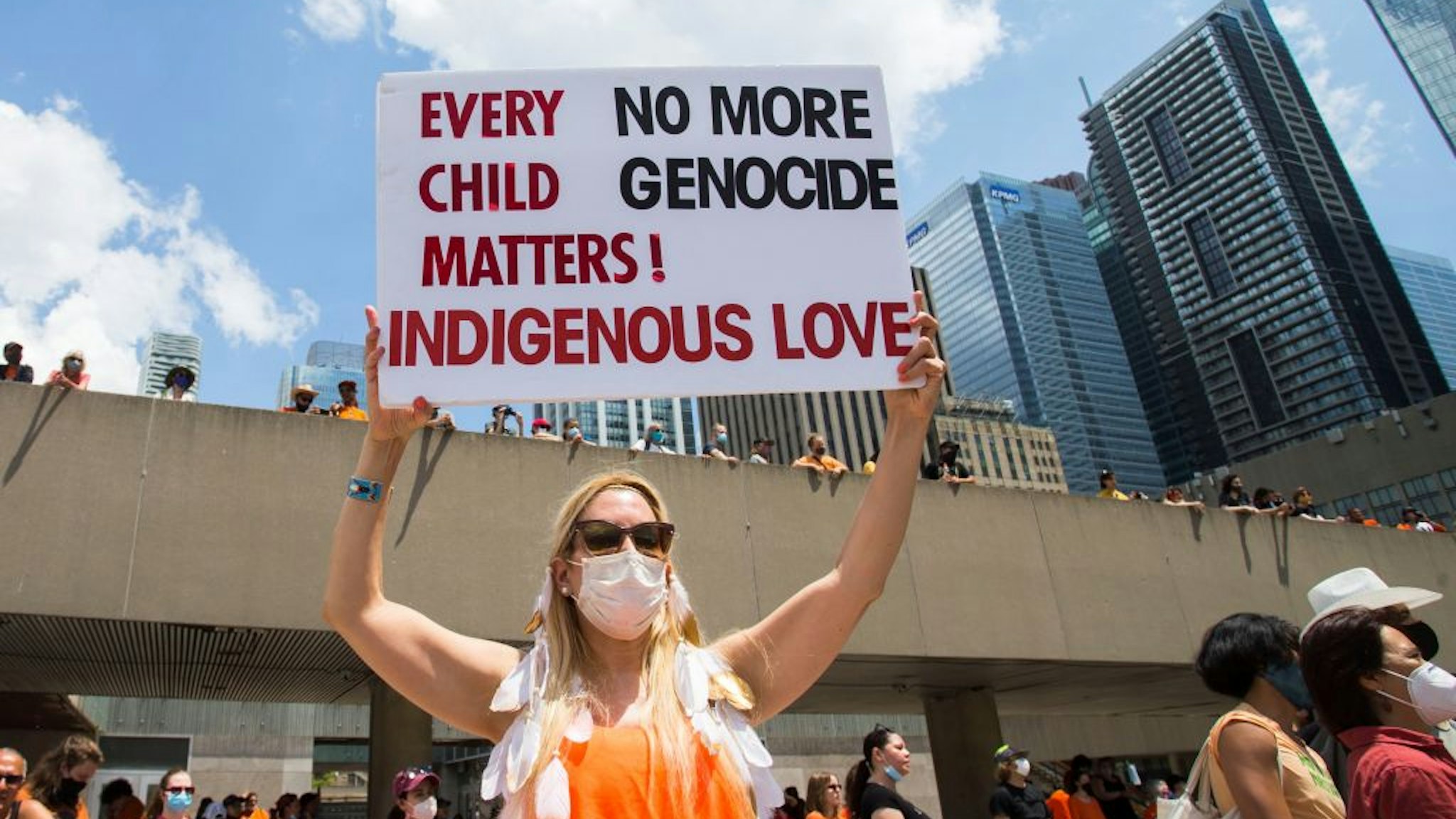 A woman holds a placard during a rally in Toronto, Canada, on July 1, 2021. Hundreds of people gathered here on Thursday to pay tribute to indigenous children whose bodies were found in mass graves near former indigenous residential schools in Canada.