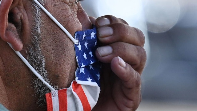 A man adjusts his American flag face mask on July 19, 2021 on a street in Hollywood, California, on the second day of the return of the indoor mask mandate in Los Angeles County due to a spike in coronavirus cases. - The US surgeon general on July 18 defended a renewed mask mandate in Los Angeles, saying other areas may have to follow and adding that he is "deeply concerned" about the Covid-19 outlook in the fall. LA County reported another 1,233 Covid-19 cases, the 11th consecutive day the number has topped 1,000. (Photo by Robyn Beck / AFP) (Photo by ROBYN BECK/AFP via Getty Images)