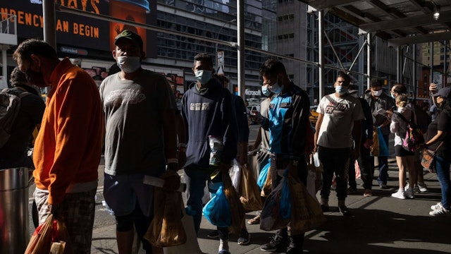 A group of migrants wait in line after arriving from Texas, outside Port Authority Bus Terminal to receive humanitarian assistance on August 10, 2022 in New York. - Texas has sent thousands of migrants from the border state into Washington, DC, New York City, and other areas. (Photo by Yuki IWAMURA / AFP) (Photo by YUKI IWAMURA/AFP via Getty Images)
