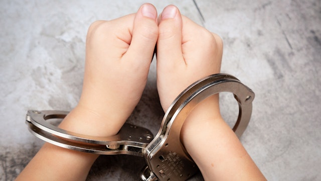 White Young Child's Hands in Jail Handcuffs - stock photo