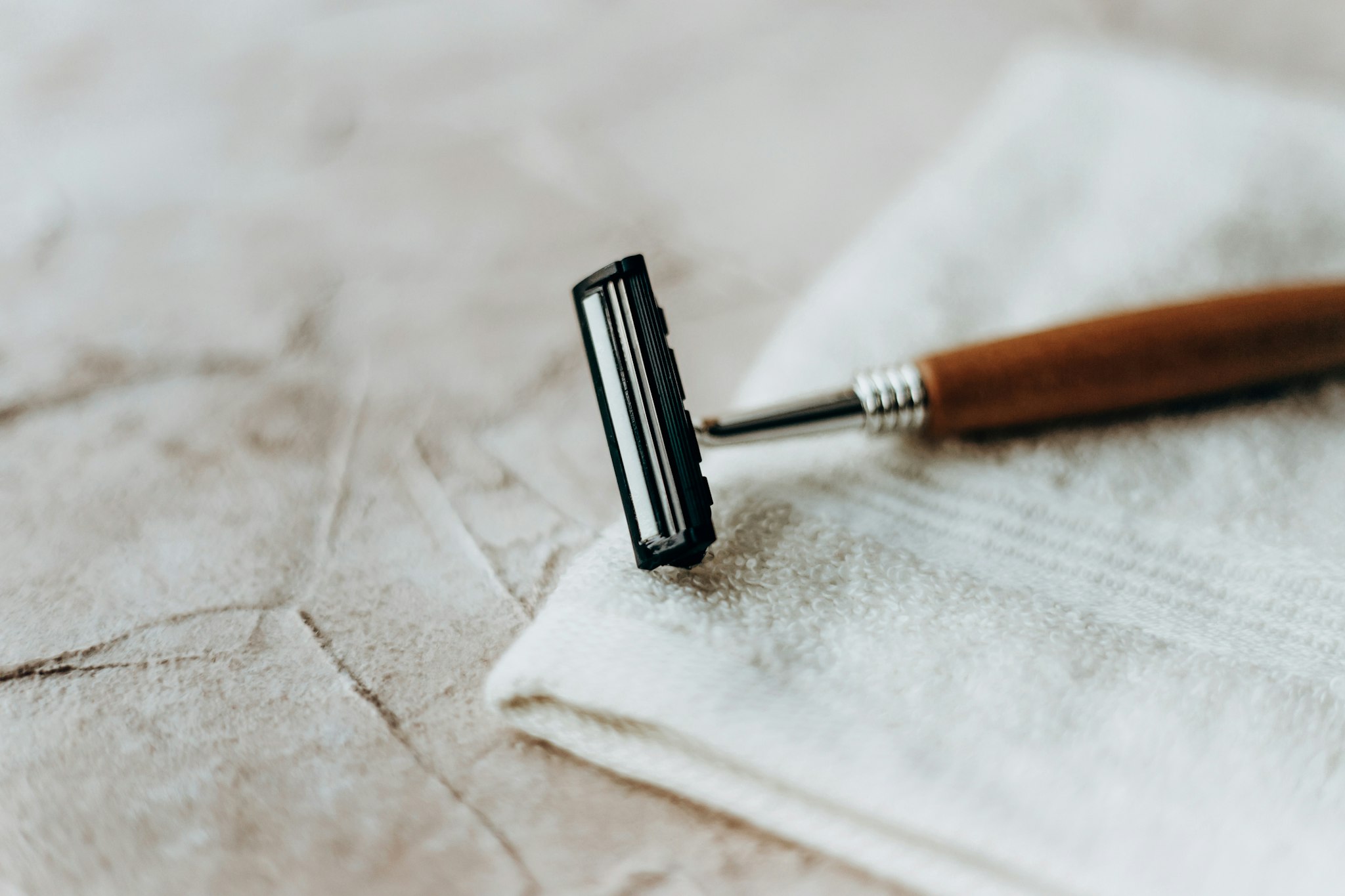 Eco razor with a wooden handle lies on a white towel on a beige background
