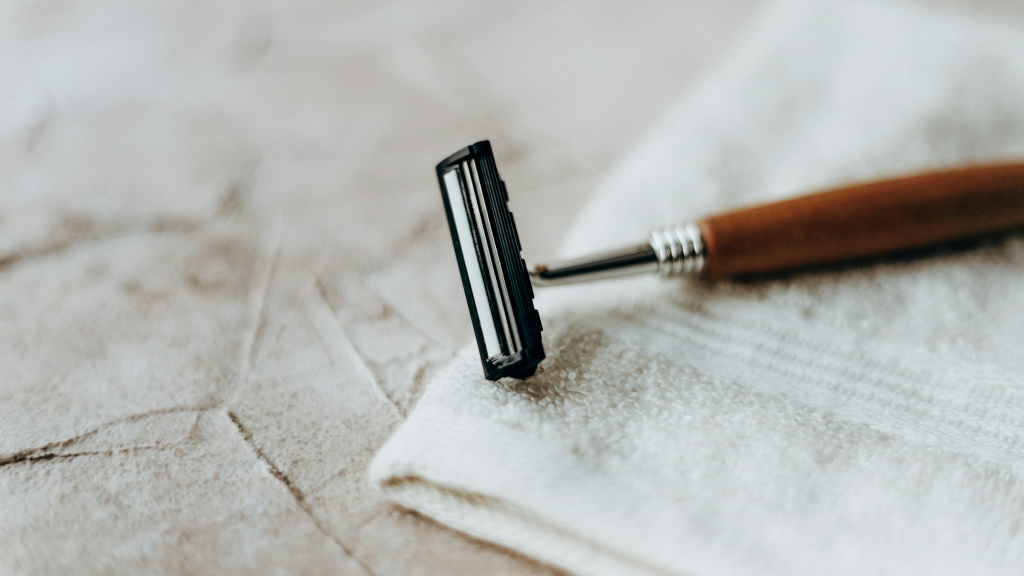 Eco razor with a wooden handle lies on a white towel on a beige background