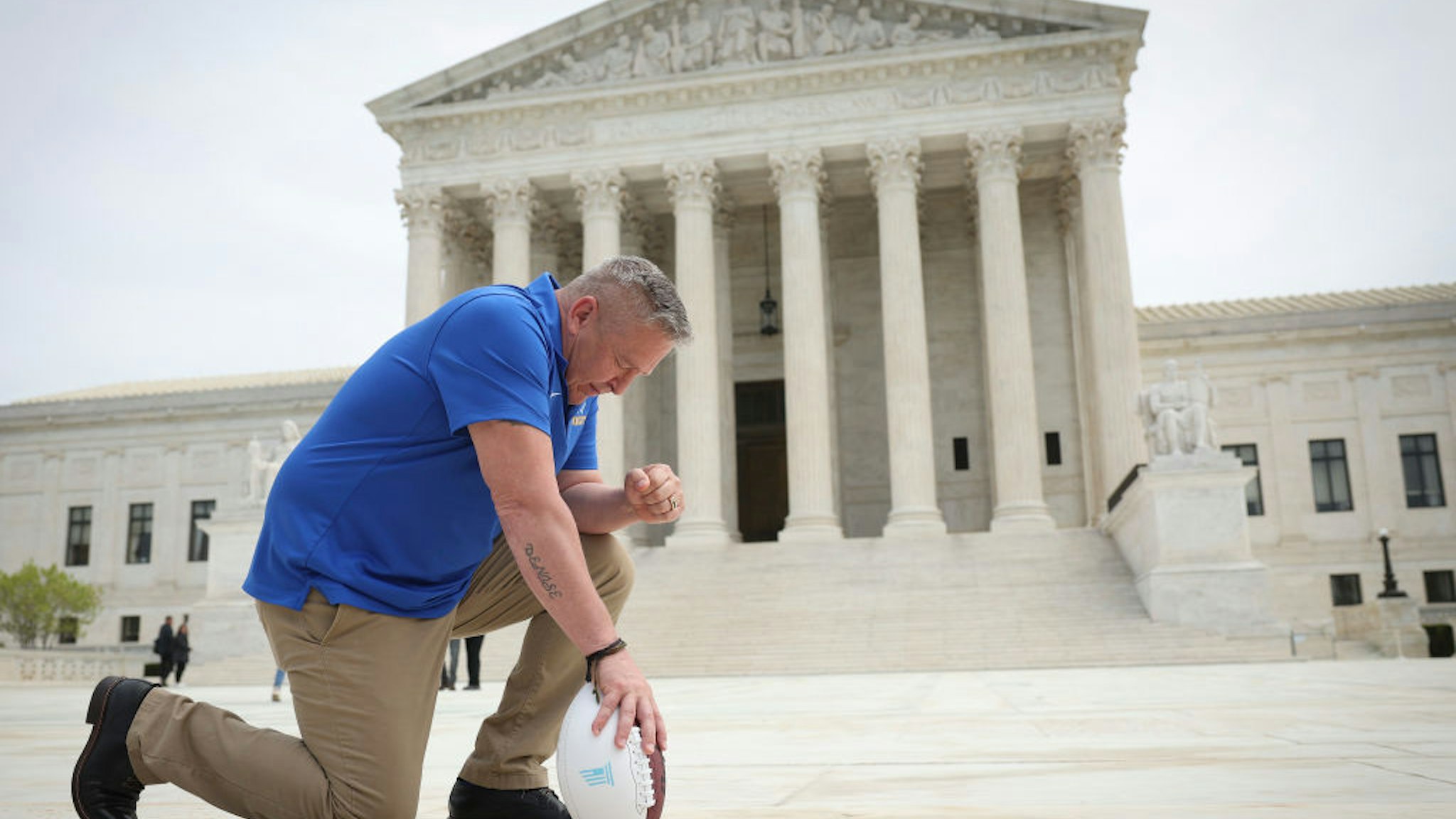 WASHINGTON, DC - APRIL 25: Former Bremerton High School assistant football coach Joe Kennedy takes a knee in front of the U.S. Supreme Court after his legal case, Kennedy vs. Bremerton School District, was argued before the court on April 25, 2022 in Washington, DC. Kennedy was terminated from his job by Bremerton public school officials in 2015 after refusing to stop his on-field prayers after football games.