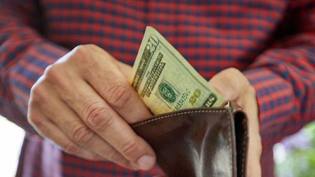 Close up on man's hand holding twenty dollar bill, US currency, cash