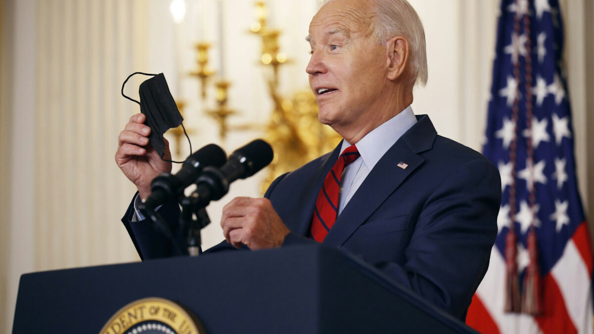 U.S. President Joe Biden holds up his mask while delivering remarks to an audience of leaders from the International Longshore and Warehouse Union (ILWU) and the Pacific Maritime Association (PMA) during an event to congratulate them on finalizing a new labor contract in the State Dining Room at the White House on September 06, 2023 in Washington, DC.