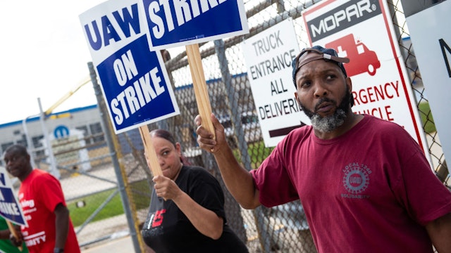 UAW members and workers at the Mopar Parts Center Line, a Stellantis Parts Distribution Center in Center Line, Michigan, hold signs after walking off their jobs at noon on September 22, 2023 and picketed outside the facility. The US auto workers union expanded a potentially economically and politically damaging strike against two of Detroit's "Big Three" on September 22, 2023 -- and invited President Joe Biden to support workers on the picket line. UAW President Shawn Fain announced a strike of all 38 US parts and distribution centers at General Motors and Stellantis, where negotiations are stalled. (Photo by Matthew Hatcher / AFP)