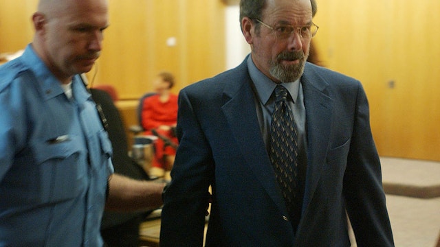 Dennis L. Rader (R), suspected of being the BTK serial killer, is escorted from the Sedgwick County courtroom after his arraignment May 3, 2005 in Wichita, Kansas. Rader, charged with 10 counts of murder, entered a plea of not guilty on all counts.