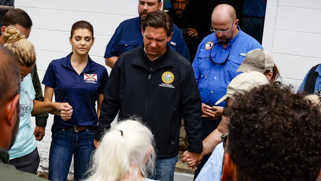 Ron DeSantis, governor of Florida and 2024 Republican presidential candidate, center, and Casey DeSantis, Florida's first lady, left, pray during a visit after Hurricane Idalia in Horseshoe Beach, Florida, US, on Thursday, Aug. 31, 2023. Florida has started to dig out from the aftermath of Idalia, which weakened to a tropical storm even as it brought heavy rain across Georgia and the Carolinas, caused billions of dollars in damage, left hundreds of flights grounded and thousands without power.