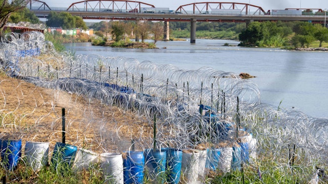 The edge of the Rio Grande in Eagle Pass' Shelby Park is lined with concertina wire in Eagle Pass, Texas on August 24, 2023. The buoys were installed in the river at a popular migrant crossing point in July on the instructions of conservative Texas Governor Greg Abbott, along with large razor-wire barriers on shore, sparking a rebuke from both Washington and Mexico City.