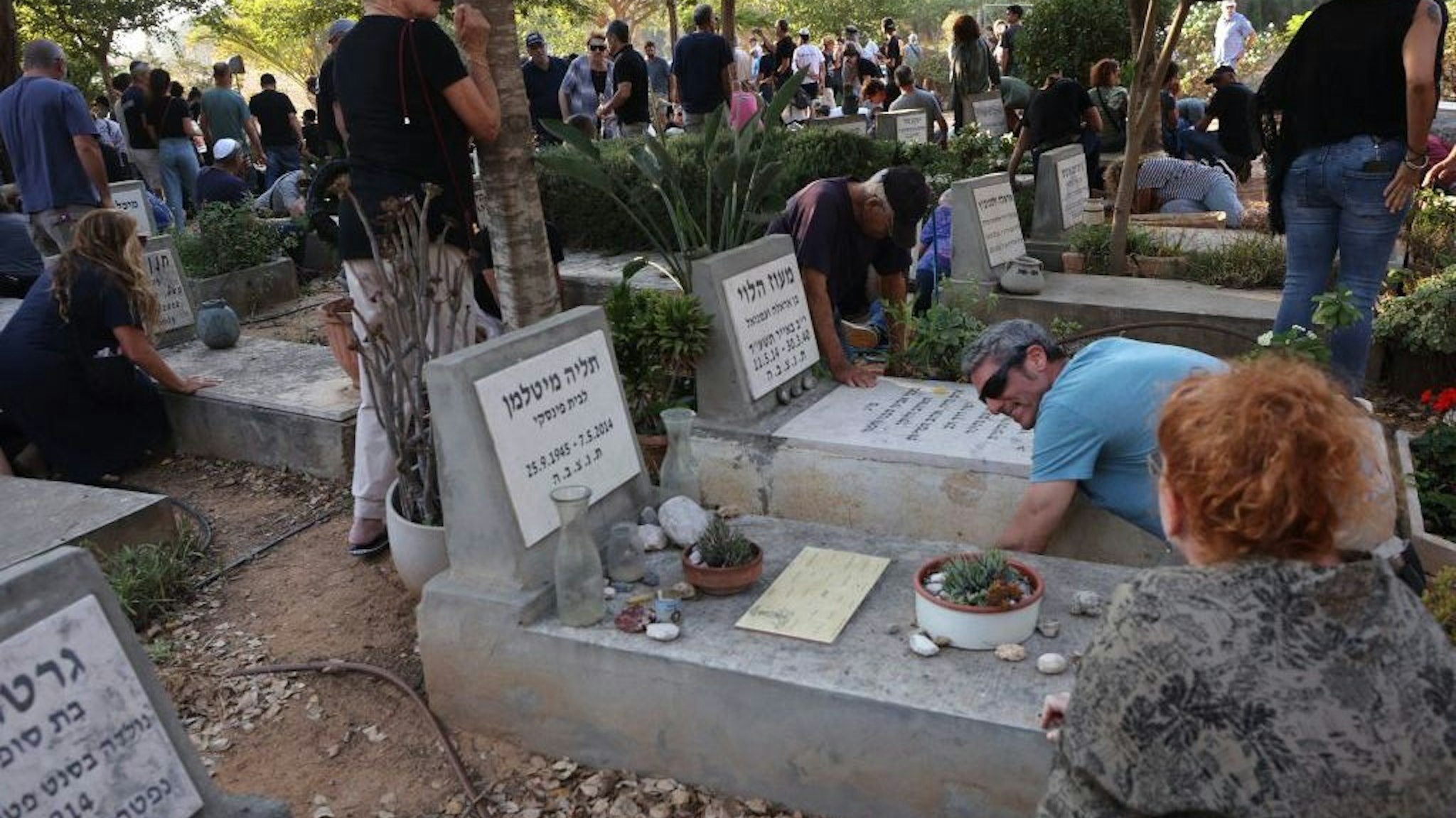 Mourners duck for cover upon hearing sirens warning of incoming rockets during the funeral of Tom Godo, killed during the attack by Palestinian Hamas militants on the Kibbutz Kisuffim last week, in Kibbutz Naan near Tel Aviv on October 12, 2023. (Photo by GIL COHEN-MAGEN/AFP via Getty Images)