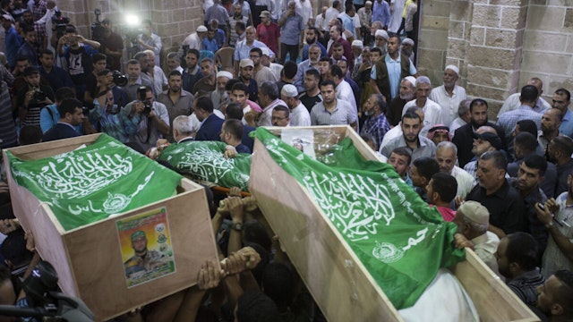 GAZA, GAZA STRIP, PALESTINE - 2018/07/26: (EDITORS NOTE: Image depicts death.) Mourners carry the coffins of Palestinian Hamas militants who were killed in Israeli tank fire, during their funeral at a mosque in Gaza City. The military wing of Gaza's rulers Hamas have vowed revenge after Israeli strikes late July 25 killed three members of the group in the latest flare-up of violence. Israel said the artillery fire late Wednesday was in retaliation for shots fired at troops along the border which injured one soldier.