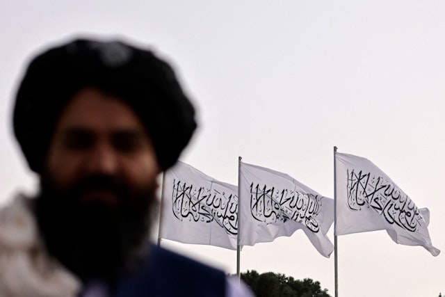 A Taliban fighter is pictured against the backdrop of Taliban flags installed at the Hamid Karzai International Airport in Kabul on September 11, 2021. (Photo by Karim SAHIB / AFP) (Photo by KARIM SAHIB/AFP via Getty Images)