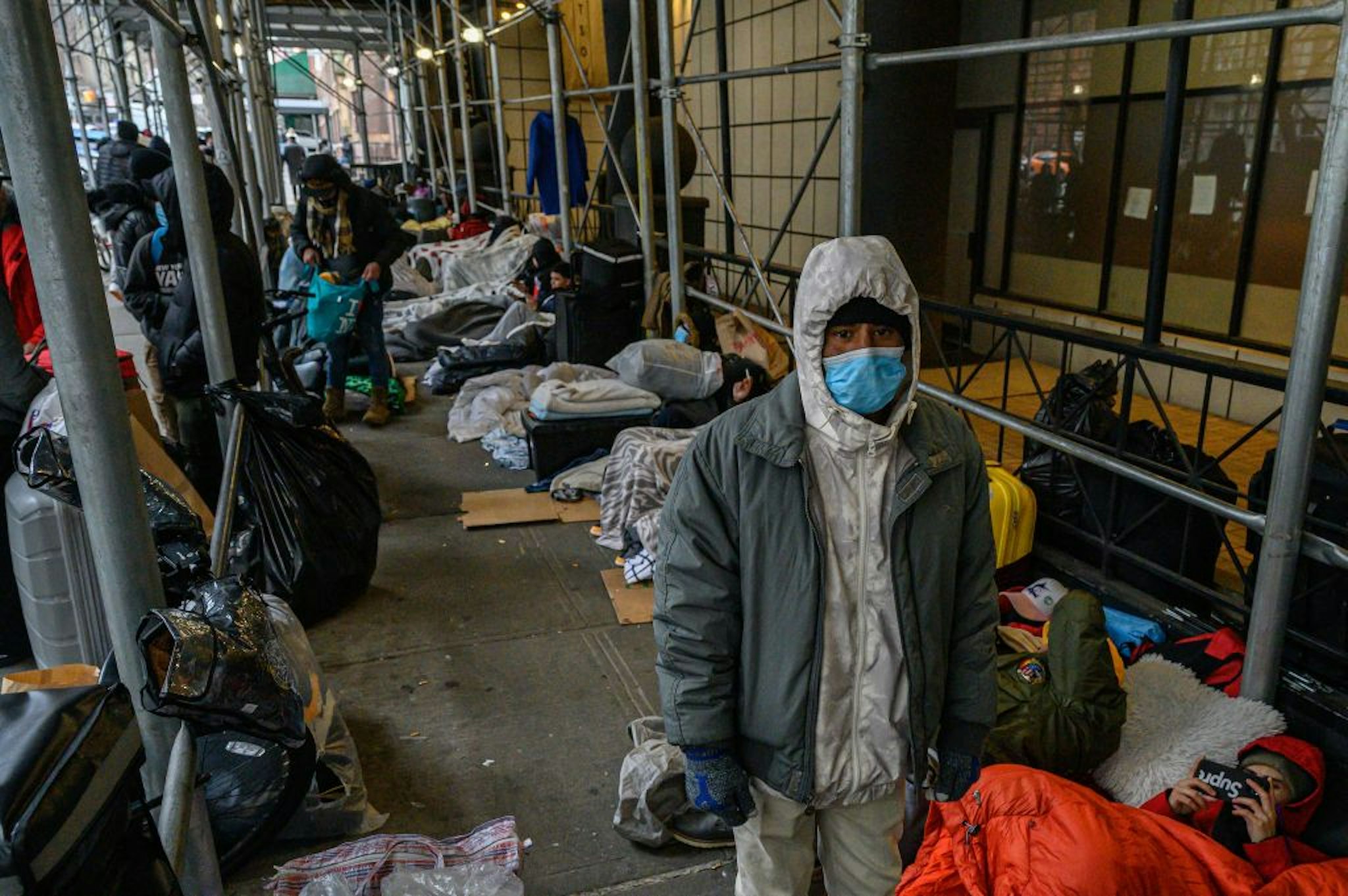 TOPSHOT - Migrants camp outside a hotel where they had previously been housed, as they resist efforts by the city to relocate them to a Brooklyn facility for asylum seekers, in the Hells Kitchen neighborhood of New York on January 31, 2023. - The Brooklyn facility is the city's fifth relief center amid a continued influx of asylum seekers, according to local media. (Photo by Ed JONES / AFP) (Photo by ED JONES/AFP via Getty Images)