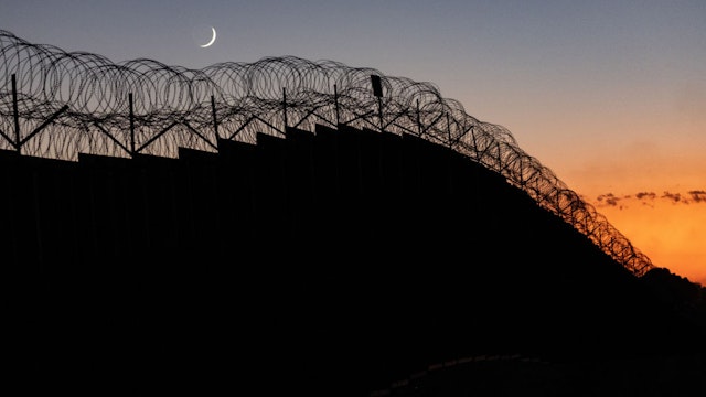 IMPERIAL SAND DUNES, CALIFORNIA - SEPTEMBER 27: A crescent moon appears over the U.S.-Mexico border fence on September 27, 2022 at the Imperial Sand Dunes, California. The number of immigrants crossing into the U.S. in 2022 is set to be the highest in recent history, surpassing the historic highs of 2021.