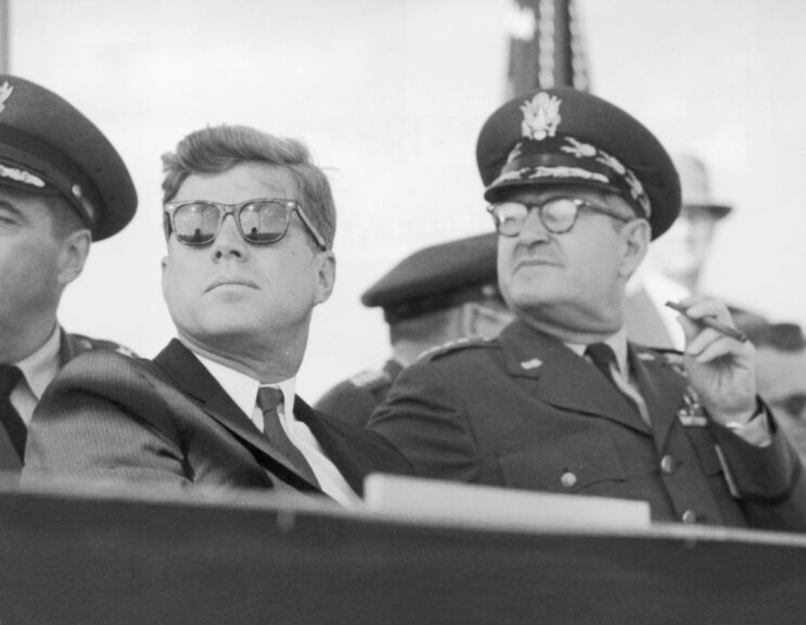 circa 1962: American president John F Kennedy (1917 - 1963), wearing dark sunglasses, sits next to US Air Force Chief of Staff Curtis LeMay (1906 - 1990, L). (Photo by Hulton Archive/Getty Images)