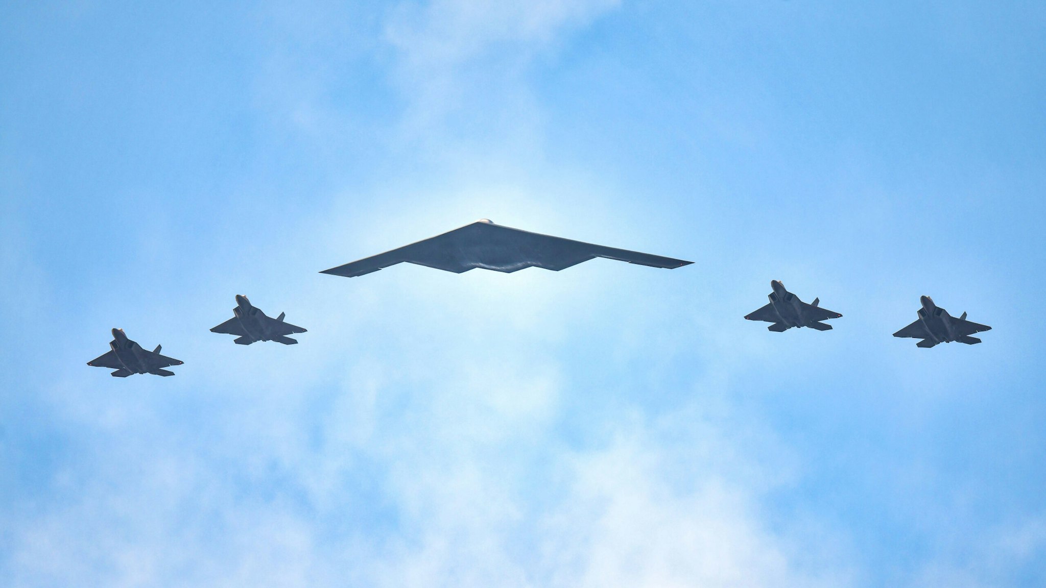 NEW YORK, NY - JULY 04: F-22 Raptors and a B-2 Stealth Bomber (C) fly over the Hudson River during the "Salute to America" military flyover on July 4, 2020 in New York City.