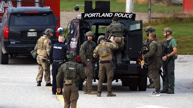 Lisbon, ME - October 26: Law enforcement officials load into a tactical vehicle at Lisbon High School at daybreak as a manhunt resumes for the suspect in a mass shooting that took place the day prior.