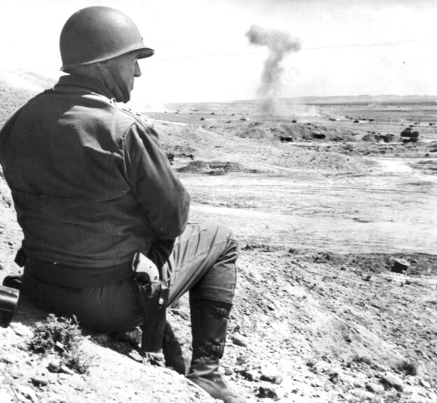 American military commander Lieutenant General George S. Patton (1885 - 1945) sits on the sand and watches a tank battle in Tunisia, 1943. (Photo by PhotoQuest/Getty Images)