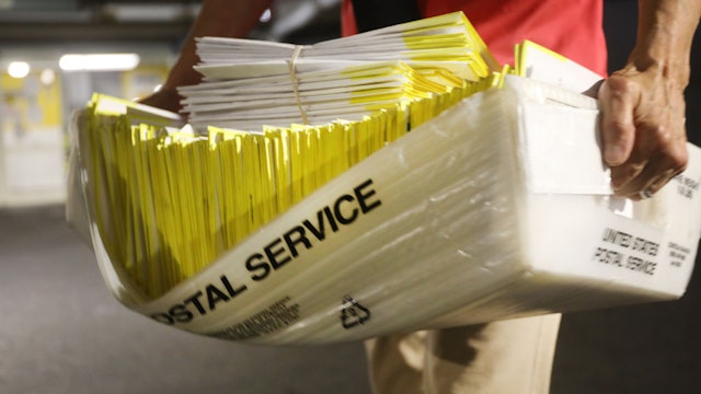 HARTFORD, CONNECTICUT - AUGUST 11: A polling worker holds 2020 presidential primary ballots that were dropped at a post office and brought to a government center to be processed and counted at the Stamford Government Center on August 11, 2020 in Hartford, Connecticut. Due to the ongoing COVID-19 pandemic, Connecticut Governor Ned Lamont signed an executive order allowing all registered voters to vote absentee in the August 11, 2020 primary. Connecticut has also experienced fallout from the recent tropical storm, which knocked out power to half of the state at its peak. President Trump has been critical of the absentee ballot process saying it contributes to voter fraud.