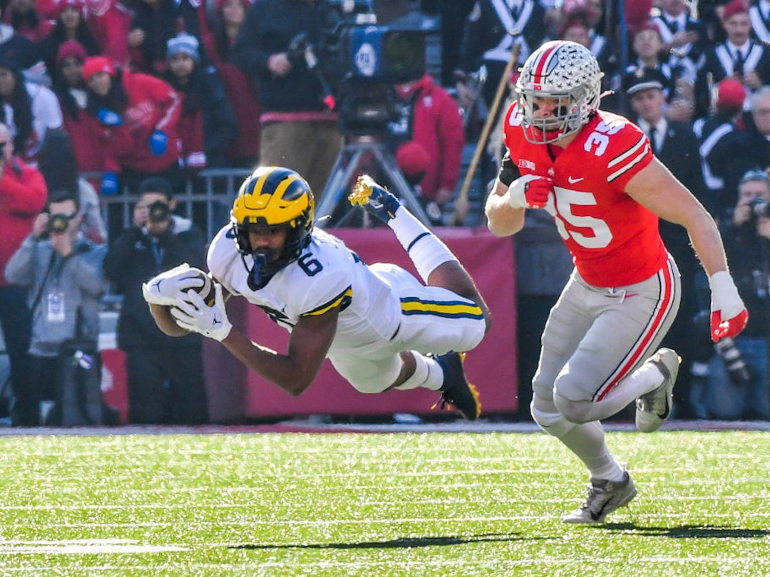COLUMBUS, OHIO - NOVEMBER 26: Cornelius Johnson #6 of the Michigan Wolverines dives for yards while chased by Tommy Eichenberg #35 of the Ohio State Buckeyes during the first half of a college football game at Ohio Stadium on November 26, 2022 in Columbus, Ohio. (Photo by Aaron J. Thornton/Getty Images)