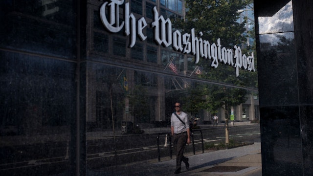 A man walks past The Washington Post on August 5, 2013 in Washington, DC after it was announced that Amazon.com founder and CEO Jeff Bezos had agreed to purchase the Post for USD 250 million. Multi-billionaire Bezos, who created Amazon, which has soared in a few years to a dominant position in online retailing, said he was buying the Post in his personal capacity and hoped to shepherd it through the evolution away from traditional newsprint. AFP PHOTO/Brendan SMIALOWSKI (Photo by Brendan SMIALOWSKI / AFP) (Photo by BRENDAN SMIALOWSKI/AFP via Getty Images)