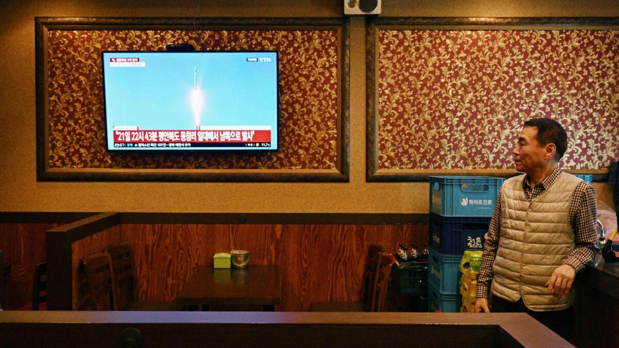 A man watches a television showing a news broadcast at a restaurant in Seoul late on November 21, 2023, after North Korea fired what it claims is a military spy satellite, Seoul's armed forces said on November 21, hours after Japan confirmed that Pyongyang had warned it of an imminent launch.