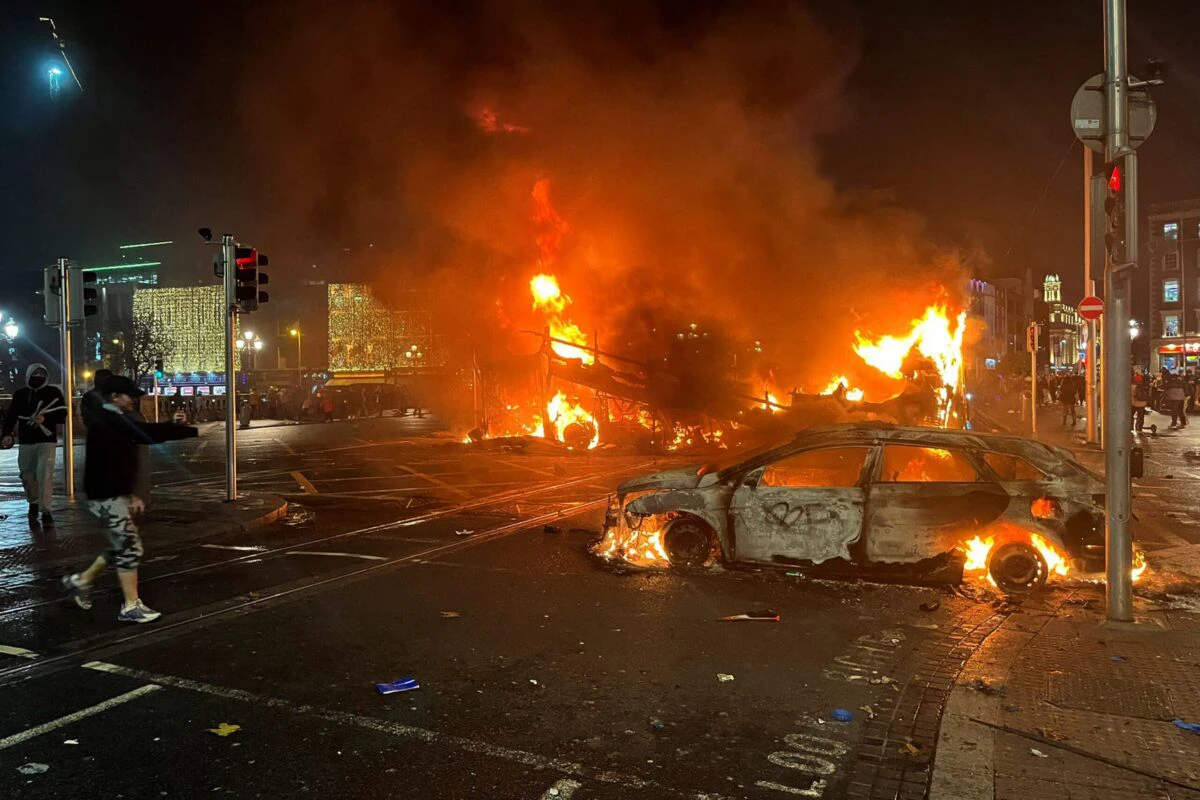 Flames rise from the car and a bus, set alight at the junction of Bachelors Walk and the O'Connell Bridge, in Dublin on November 23, 2023, as people took to the streets following the stabbings earlier in the day. Protesters in Dublin on Thursday torched a car and fought police, an AFP journalist reported, after three children were injured in a suspected school stabbing that social media rumours attributed to a foreign national.