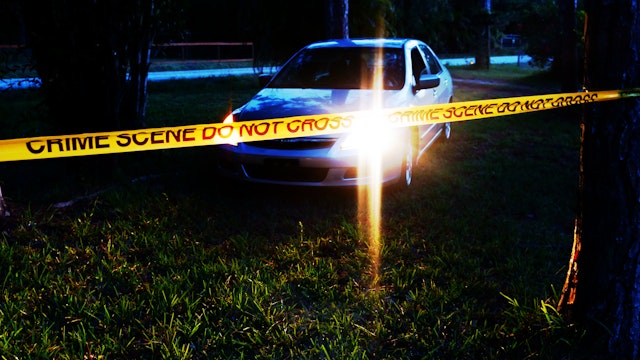 Car at crime scene in wooded area at night - stock