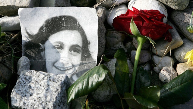 A picture of Anne Frank lies in front of the memorial stone for Jewish girl Anne Frank, author of "The Diary of a Young Girl", and her sister Margot, 28 October 2007 on the grounds of the new Bergen-Belsen Memorial. Both girls died at the concentration camp a few weeks before it was liberated by British troops in April 1945. The Bergen-Belsen Memorial, which is situated sixty kilometres north-east of Hanover, is located on the grounds of the former Prisoner of War and concentration camps, marked graves and monuments hold reminders of the suffering and deaths of its prisoners. A documentation centre illustrates the history of the camp and its victims. AFP PHOTO DDP/NIGEL TREBLIN GERMANY OUT (Photo credit should read NIGEL TREBLIN/DDP/AFP via Getty Images)