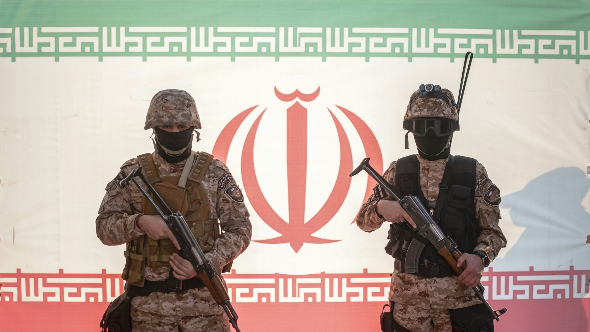 Two Islamic Revolutionary Guard Corps (IRGC) armed military personnel pose for a photograph in front of an Iran flag during a pro-government protest rally in southern Tehran, December 29, 2022. Pro-government protest rally held in support of Iran's Supreme Leader Ayatollah Ali Khamenei and in opposition to recent unrest following the death of Mahsa Amini, a 21-year-old Iranian-Kurd.
