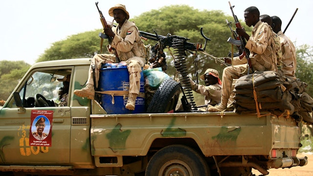 Sudanese members of the Rapid Support Forces, a paramilitary force backed by the Sudanese government to fight rebels and guard the Sudan-Libya border, ride in the back of a Toyota pickup truck as they prepare to receive President Omar al-Bashir during his visit to the town of Umm al-Qura, northwest of Nyala in South Darfur province, on September 23, 2017. Bashir, wanted by the International Criminal Court on charges of genocide and war crimes related to the conflict in Darfur, is touring the region ahead of a US decision to be made on October 12, 2017 on whether to permanently lift a decades-old trade embargo on Sudan.