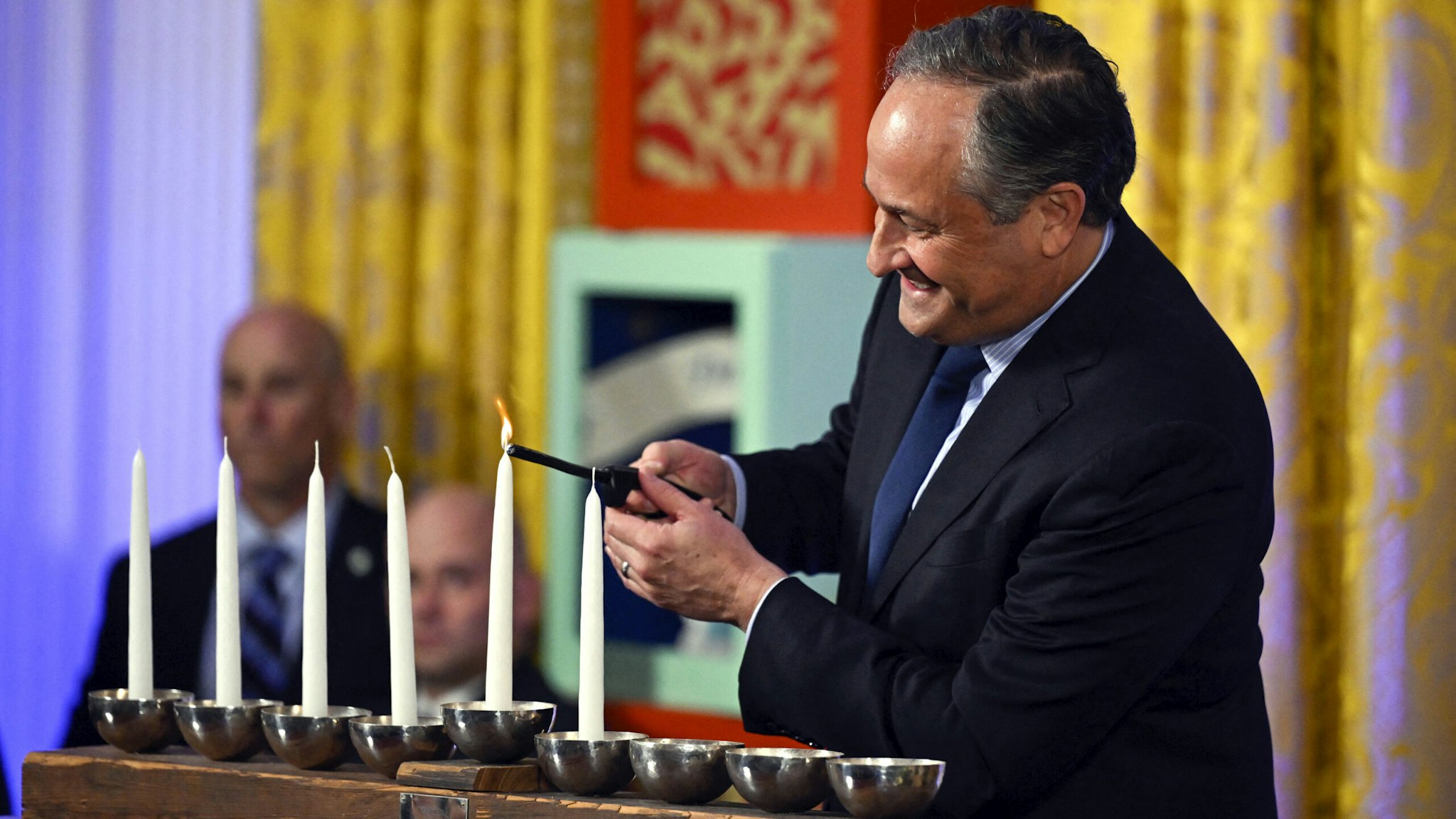 US Second Gentleman Doug Emhoff lights the first flame on a Menorah candle during a Hanukkah reception in the East Room of the White House in Washington, DC, on December 11, 2023.