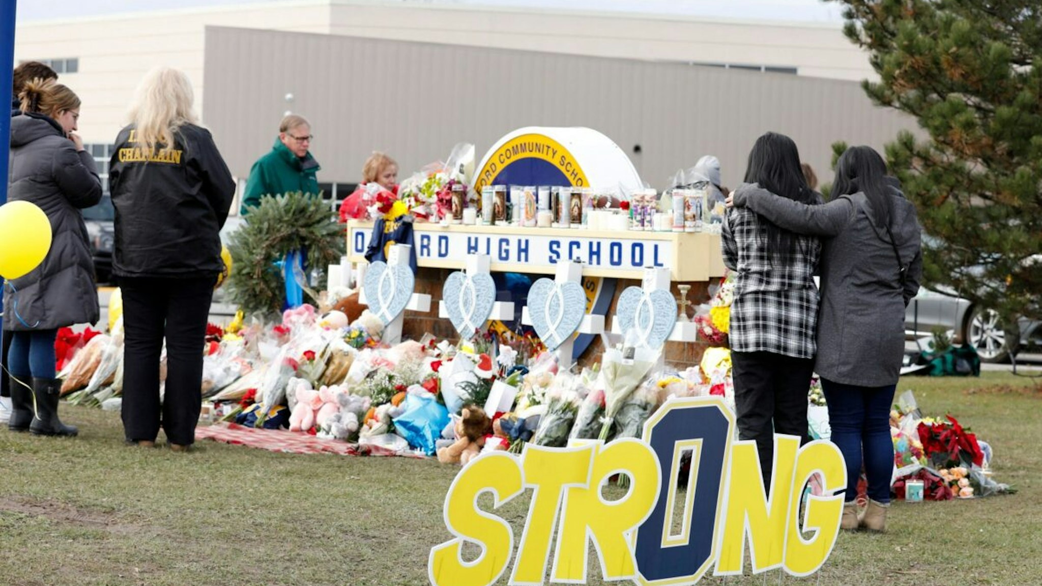 People gather at the memorial for the dead and wounded outside of Oxford High School in Oxford, Michigan on December 3, 2021. - The parents of a 15-year-old boy who shot dead four students at a high school in the US state of Michigan with a gun bought for him by his father just days earlier were charged with involuntary manslaughter.