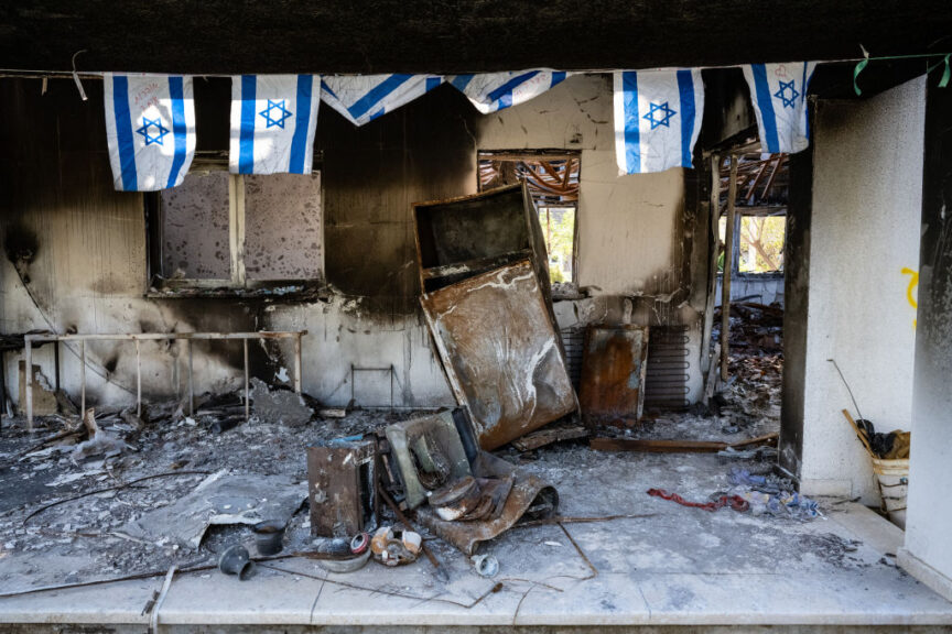 NIR OZ, ISRAEL - DECEMBER 6: Israeli flags hang over a burned house, as Israeli residents of the Nir Oz kibbutz still grapple with being overrun two months earlier in an attack by Palestinian Hamas militants from the nearby Gaza Strip, in which 46 out of 417 people were killed and 71 were taken hostage, on December 6, 2023 in Nir Oz, Israel. The Hamas attack against on October 7 killed 1200 Israelis and left 240 people taken hostage, and triggered a military response that Palestinian officials say has left more than 18,000 dead. A week-long ceasefire and hostage-for-prisoner exchange ended on Dec. 1, with Israeli leaders vowing to continue their offensive until defeat of Hamas. (Photo by Scott Peterson/Getty Images)