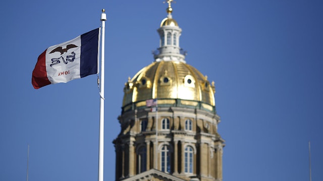 The Iowa state flag flies outside the State Capitol Building in Des Moines, Iowa, U.S., on Friday, Jan. 29, 2016. As the first in the nation Iowa caucuses approaches, where registering your vote isn't as simple as casting a ballot, the state is starting to thrum with nervous energy.
