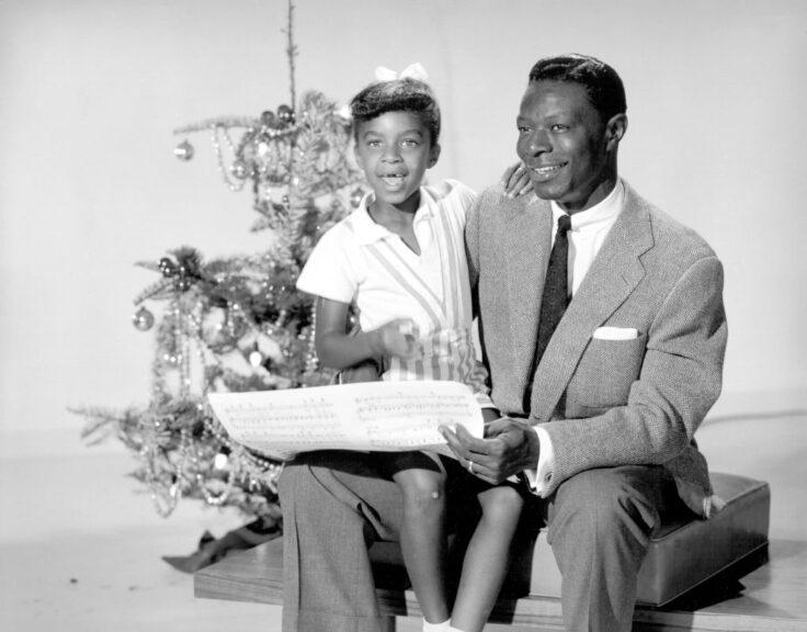 CIRCA 1955: Singer Nat "King" Cole and his daughter Natalie Cole pose for a portrait session in front of a Christmas tree in circa 1955. (Photo by Michael Ochs Archives/Getty Images)
