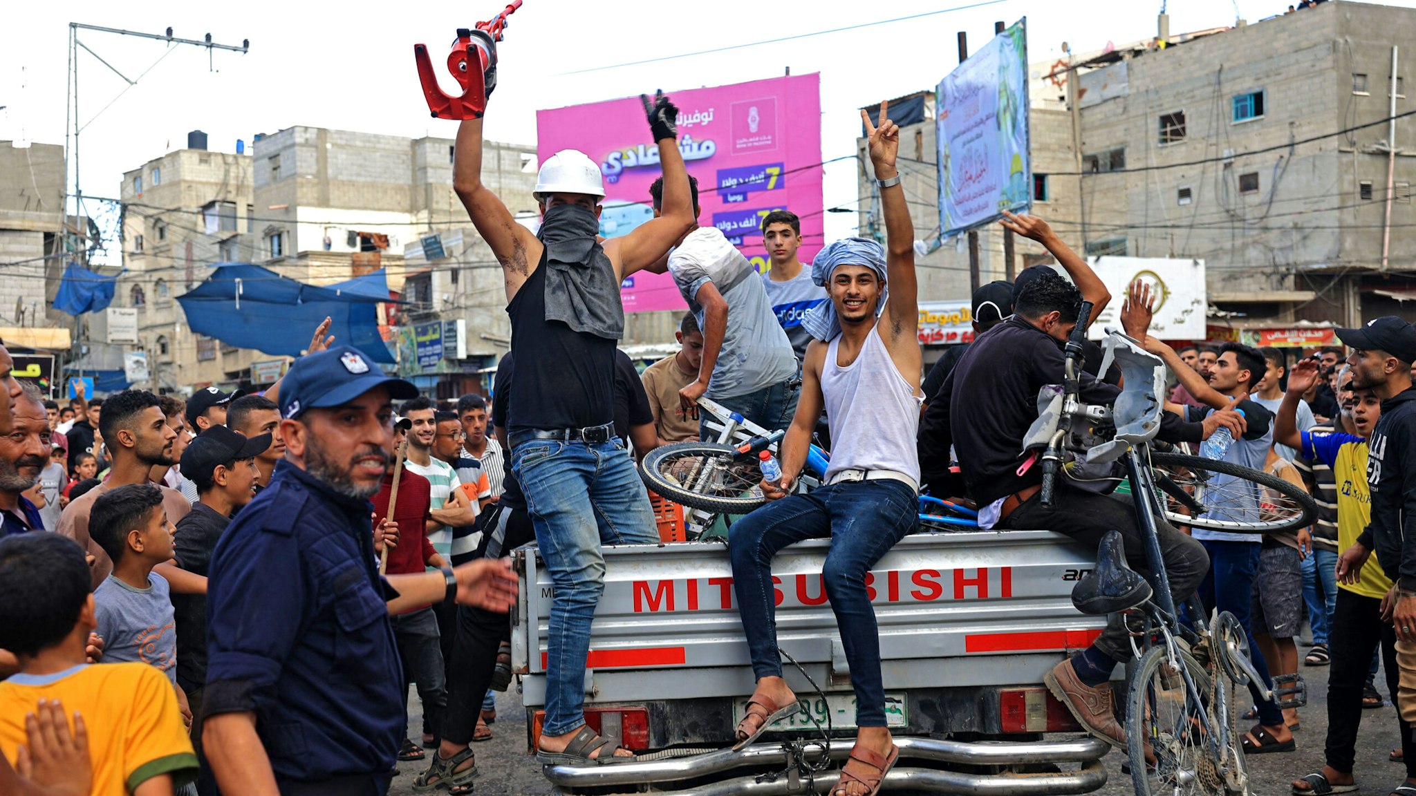 Palestinians celebrate their return after crossing the border fence with Israel from Khan Yunis in the southern Gaza Strip on October 7, 2023. Barrages of rockets were fired at Israel from the Gaza Strip at dawn as militants from the blockaded Palestinian enclave infiltrated Israel, with at least one person killed, the army and medics said.