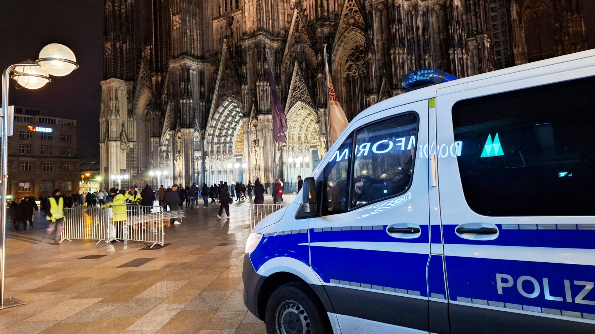 23 December 2023, North Rhine-Westphalia, Cologne: A police vehicle is parked in front of the cathedral. One day before Christmas, the police in Cologne are stepping up their protective measures due to possible plans for an attack. According to dpa, security authorities have received information about a possible plan by an Islamist group to attack Cologne Cathedral.