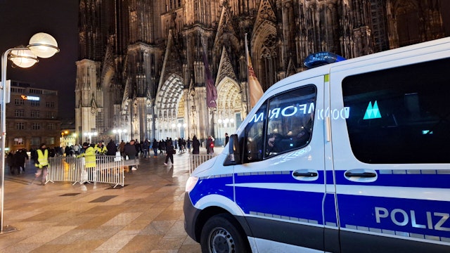23 December 2023, North Rhine-Westphalia, Cologne: A police vehicle is parked in front of the cathedral. One day before Christmas, the police in Cologne are stepping up their protective measures due to possible plans for an attack. According to dpa, security authorities have received information about a possible plan by an Islamist group to attack Cologne Cathedral.
