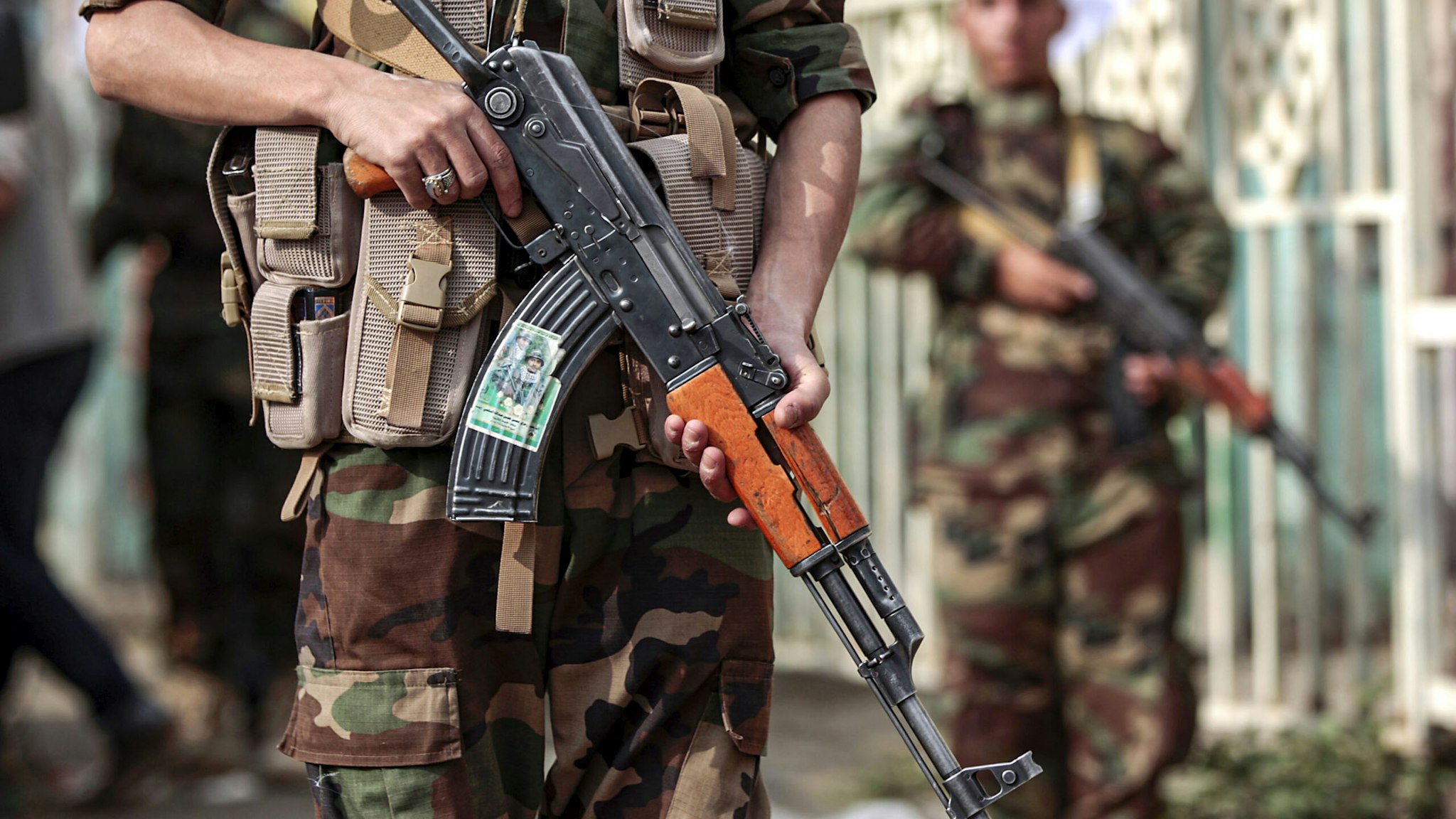 A fighter loyal to Yemen's Huthi rebels holds a Kalashnikov assault rifle showing a picture of other slain comrades as he stands guard during a rally commemorating the Shiite Muslim religious holiday of Ashura in the capital Sanaa on September 10, 2019. - Ashura is commemorated by Shiite Muslims worldwide and marks the climax of mourning rituals in the Islamic month of Muharram for the 7th century killing of Imam Hussein, the grandson of Prophet Mohammed, in the Battle of Karbala in 680 AD.