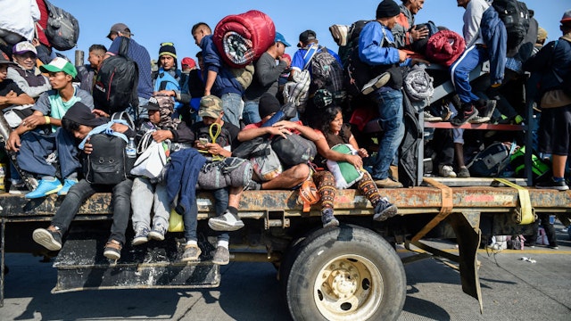 TOPSHOT - Central American migrants -mostly honduran- taking part in a caravan to the US, are pictured on board a truck heading to Irapuato in the state of Guanajuato on November 11, 2018 after spending the night in Queretaro in central Mexico. - The United States embarked Friday on a policy of automatically rejecting asylum claims of people who cross the Mexican border illegally in a bid to deter Central American migrants and force Mexico to handle them. (Photo by ALFREDO ESTRELLA / AFP)