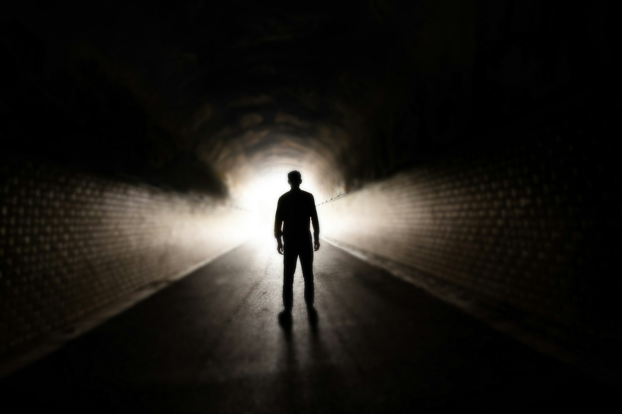 Man walking in dark tunnel - stock photo